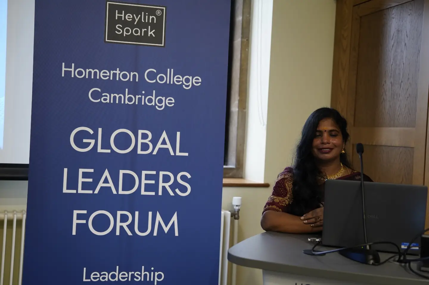 Dr. Senbagam Raja at the Global Leaders Forum backdrop at Homerton College, Cambridge